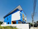 Modern two-story blue and white house with distinctive yellow windows and clear blue sky