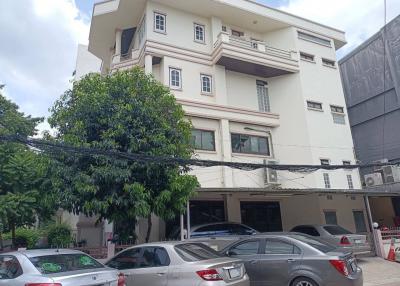 Multi-story residential building with a tree in front and parking space