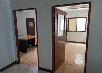 Spacious empty office with open doors, tiled flooring, and natural light