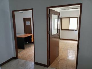 Open office doors leading to a spacious and brightly lit empty room with a single desk