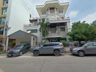 Exterior view of a multi-story residential building with parked cars in front