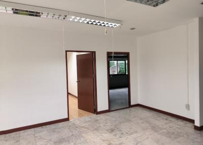 Spacious empty room with marble flooring, an open door, and a large window