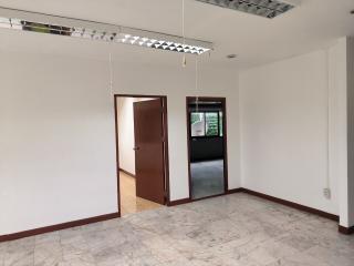 Spacious empty room with marble flooring, an open door, and a large window