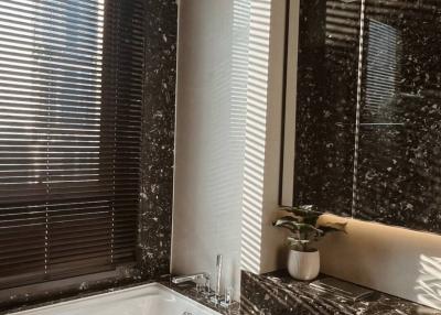 Modern bathroom with natural light featuring marble countertops, a large bathtub, and sophisticated fixtures