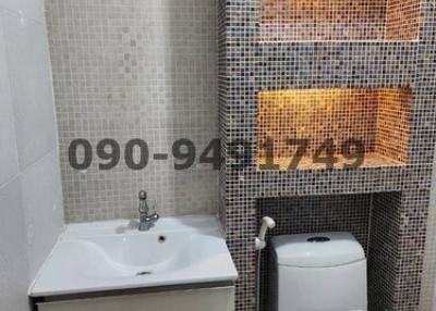 Modern bathroom with tiled walls, sink, and toilet