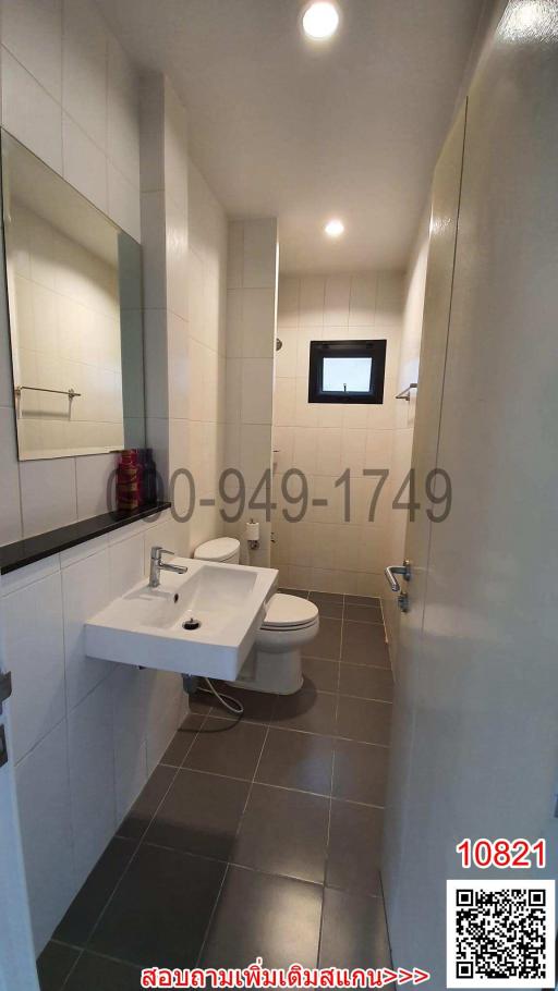 Modern bathroom with white and gray color scheme, including sink, toilet, and mirror