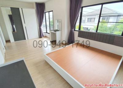 Spacious unfurnished bedroom with large window and wooden flooring in a residential home