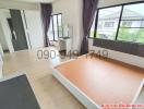 Spacious unfurnished bedroom with large window and wooden flooring in a residential home