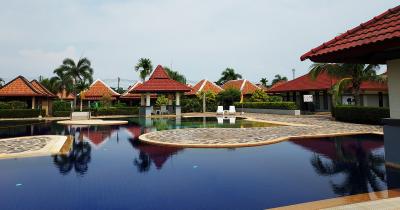 Residential complex with large swimming pool and surrounding lounging area under a sunny sky