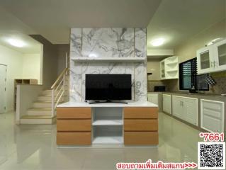 Modern living room interior with marble walls, a flat-screen TV, and staircase
