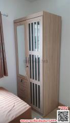 Modern wooden wardrobe in a bedroom setting with visible curtain