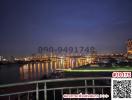 View from balcony overlooking river at dusk with city lights