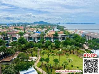 Aerial view of a residential area with row houses, green spaces, and a scenic mountain and sea backdrop