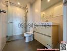 Modern bathroom interior with a glass shower cubicle, white basin, and toilet