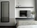 Modern bedroom interior with a large bed, mounted television, and minimalist decor