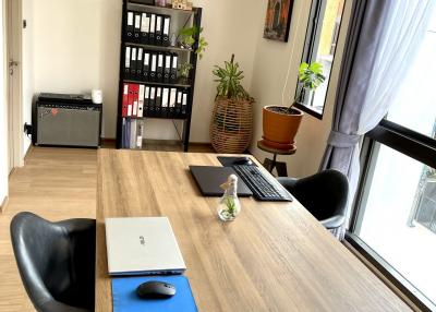 Modern home office with wooden desk and black chairs