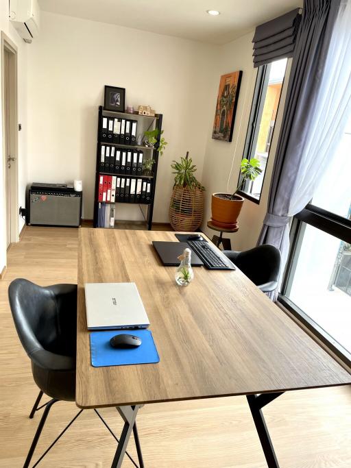 Modern home office with wooden desk and black chairs