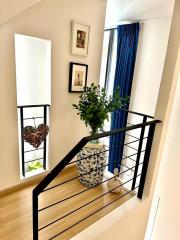 Elegant staircase with hardwood flooring, decorative railing, potted plant, and natural light