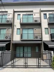 Modern three-story townhouse with balconies and a metal gate