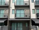 Modern three-story townhouse with balconies and a metal gate