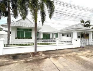 White single-story house with palm trees and white fence