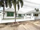 White single-story house with palm trees and white fence