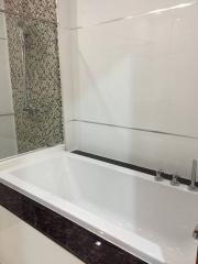 Modern bathroom with a white bathtub and elegant tiling