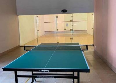 Indoor ping pong table in a well-lit recreation room with glass walls