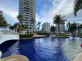 Luxurious outdoor pool area with surrounding palm trees and modern high-rise buildings