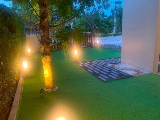 Cozy outdoor garden area with pathway lighting and artificial grass at twilight