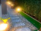 Illuminated garden path with stepping stones and artificial grass at dusk
