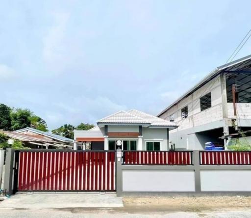 Modern suburban house with red gate and fence under a cloudy sky