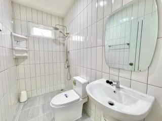 Modern white tiled bathroom with shower, sink, and toilet