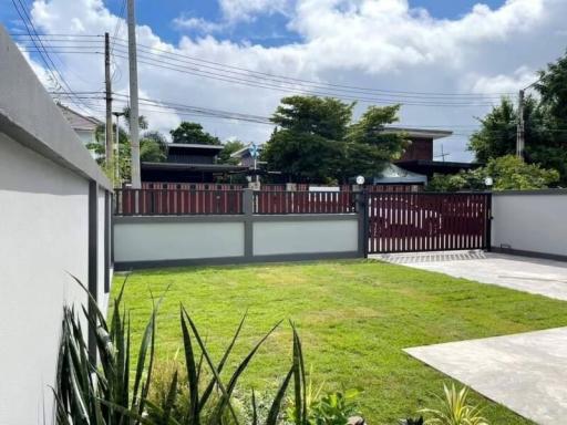 Spacious front yard with green lawn and modern fence