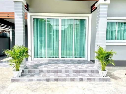 Modern house entrance with large sliding glass doors and potted plants