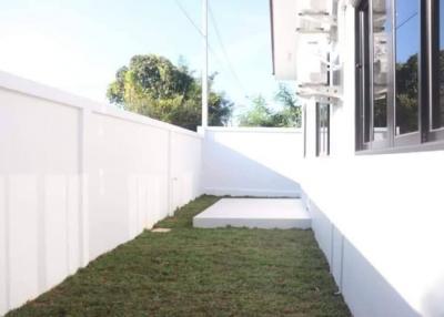 Side yard with green lawn and white fence near modern building