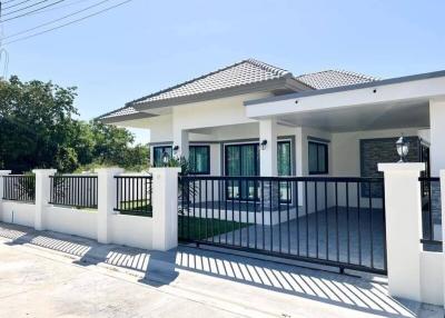 Modern single-story residential house with a white fence and spacious front yard