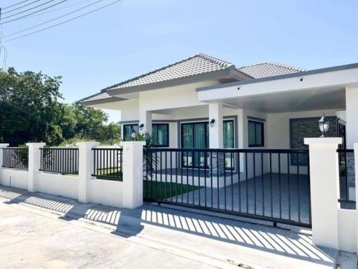 Modern single-story residential house with a white fence and spacious front yard