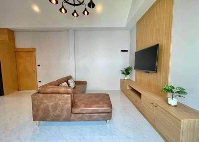 Contemporary living room with L-shaped sofa, wood-paneled TV wall, and chic lighting