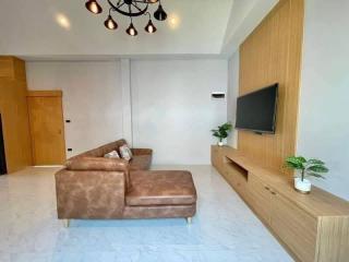 Contemporary living room with L-shaped sofa, wood-paneled TV wall, and chic lighting