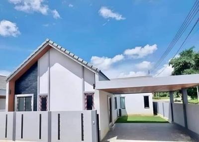 Modern single-story house with white exterior and grey roofing under blue sky