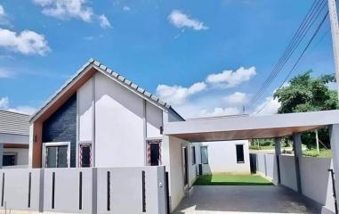 Modern single-story house with white exterior and grey roofing under blue sky