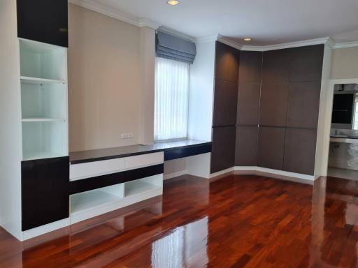 Spacious living room with gleaming hardwood floors and modern built-in shelving