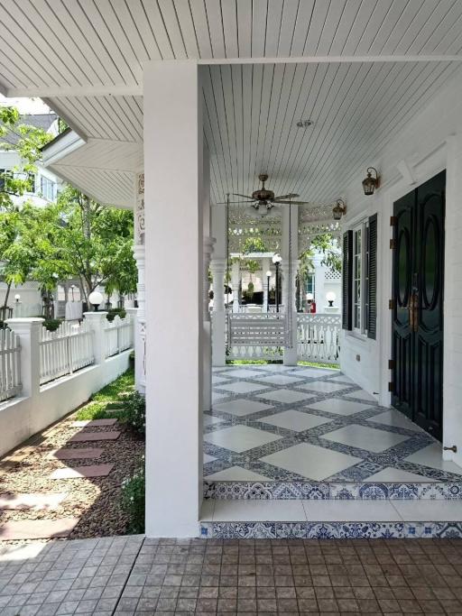 Elegant covered porch with patterned tile flooring and white wooden details