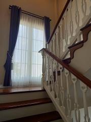 Elegant staircase with wooden handrails and large window with curtains