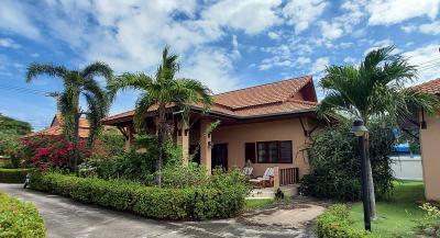 Cozy suburban house with terracotta roof, surrounded by lush greenery and a paved driveway