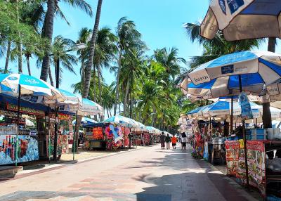 Vibrant outdoor market lined with stalls under palm trees