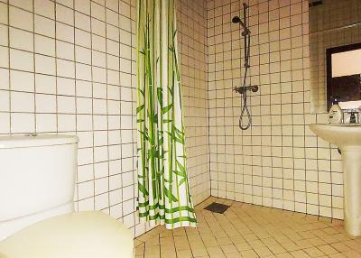 Bright bathroom interior with white tiles and green shower curtain