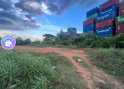 Rural landscape with a dirt path and shipping containers under a cloudy sky