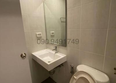 Compact bathroom with white tiles, sink, and toilet